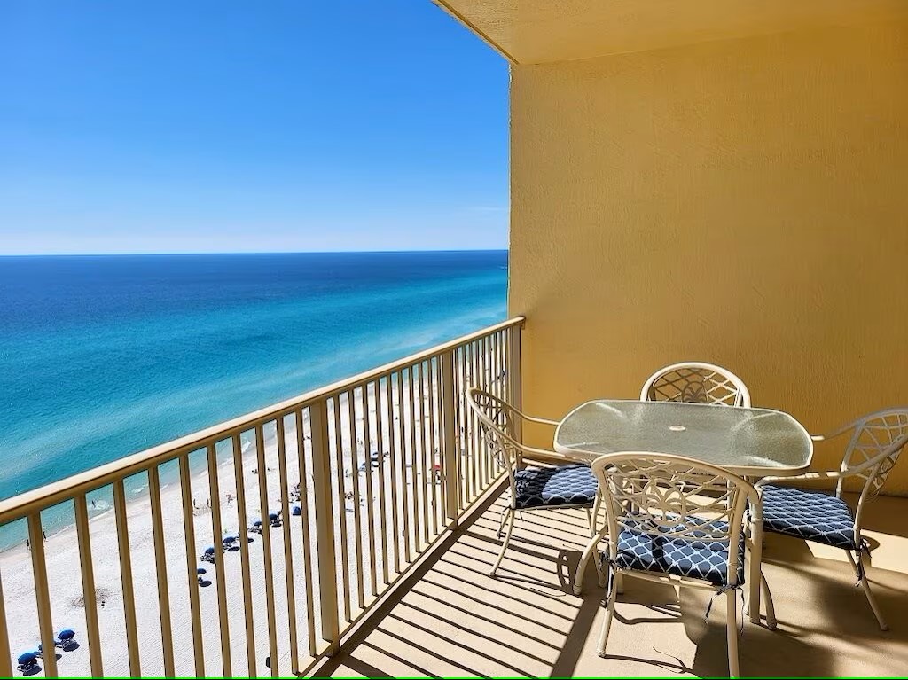 table with outside seating on balcony with water and beach view